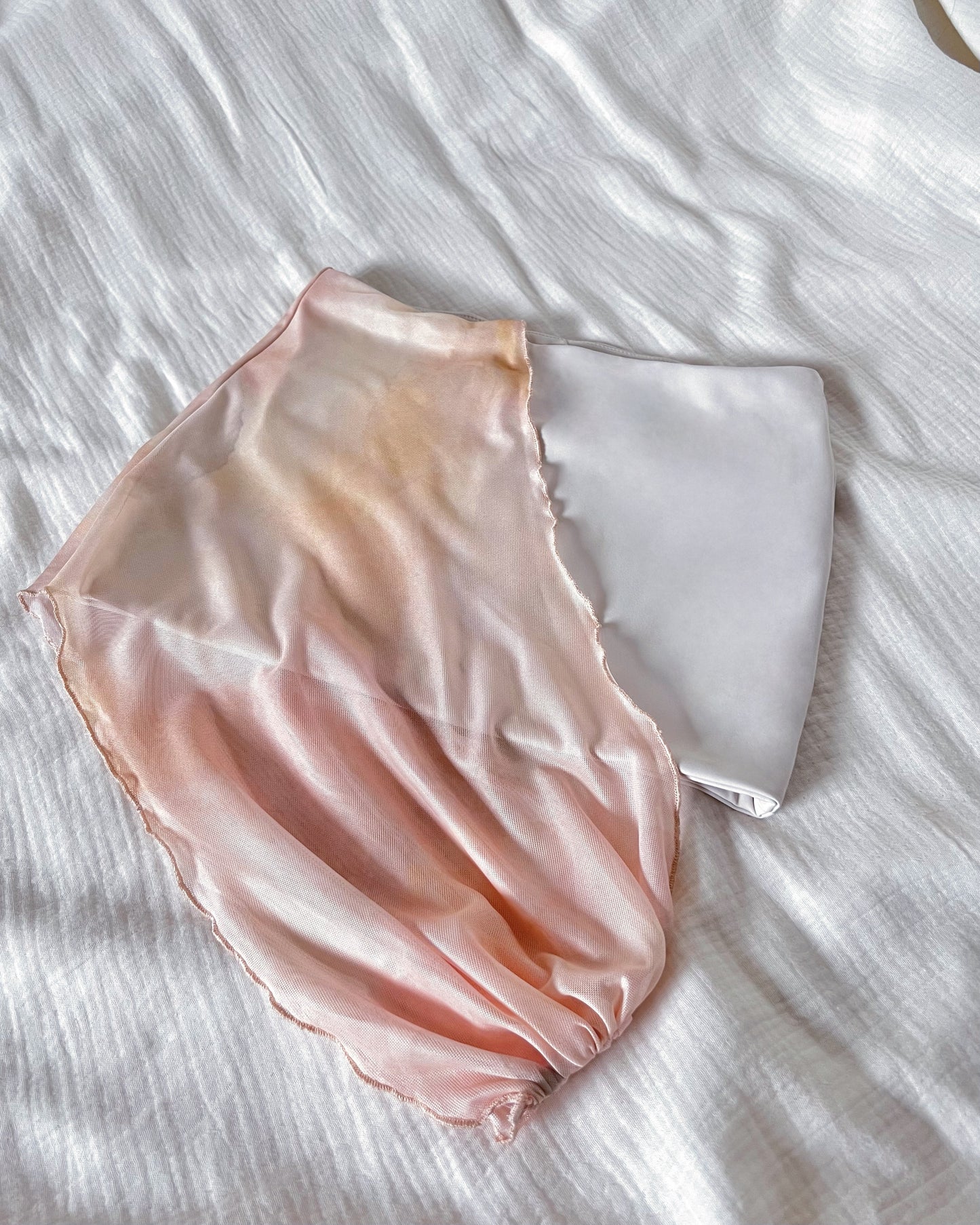 An asymmetrical sunset orange printed mini skirt in nylon fabric and mesh panel.