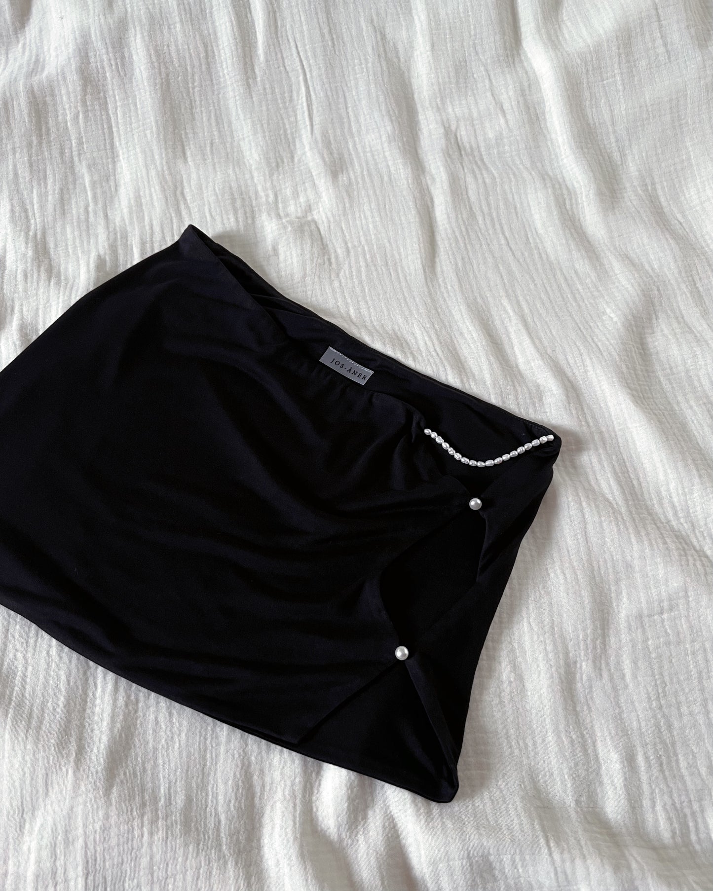 A black modal mini skirt, embellished with freshwater pearls.