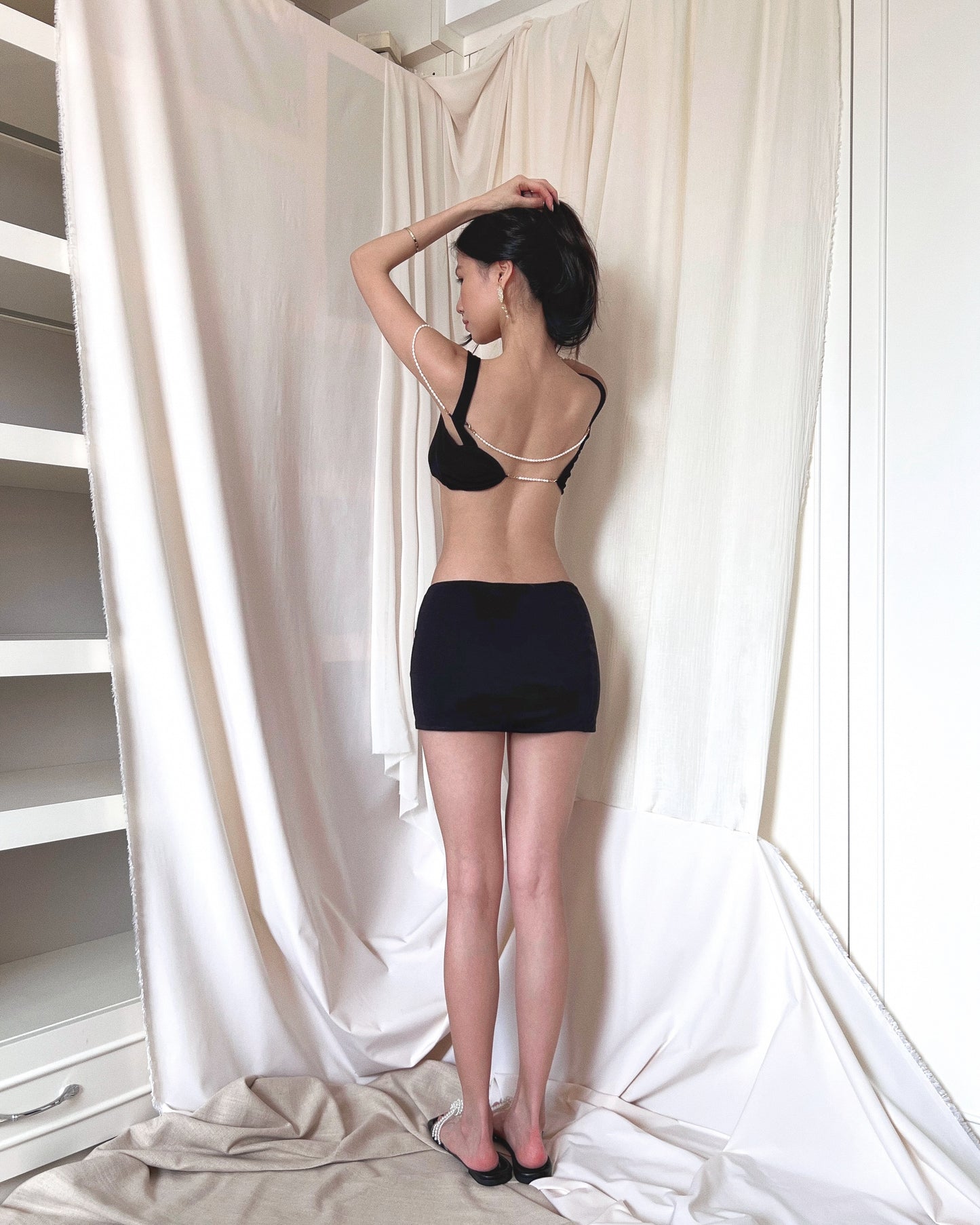 A black modal bralette top and a black modal mini skirt, both embellished with freshwater pearls. Styled with Charles & Keith pearl slides.