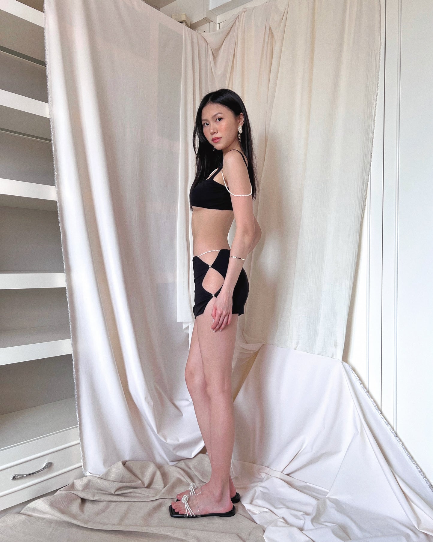 A black modal bralette top and a black modal mini skirt, both embellished with freshwater pearls. Styled with Charles & Keith pearl slides.