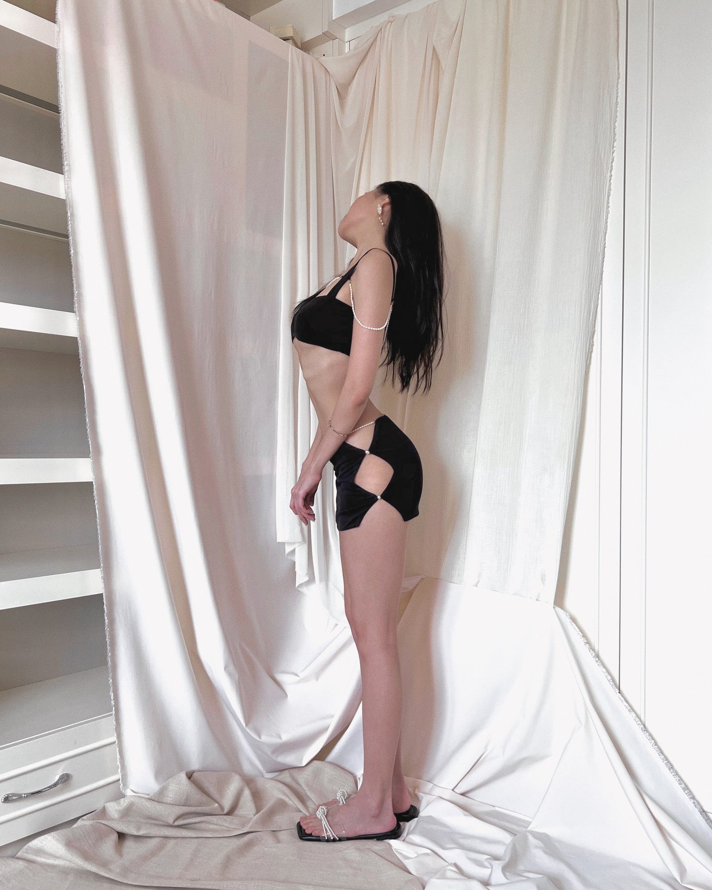 A black modal bralette top and a black modal mini skirt, both embellished with freshwater pearls. Styled with Charles & Keith pearl slides.