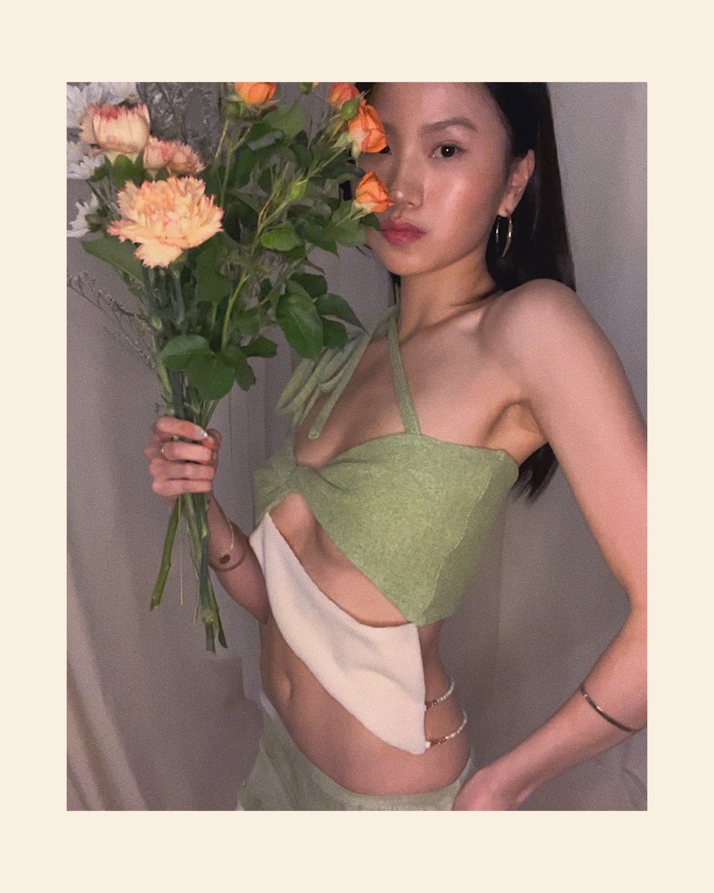 A matcha green asymmetrical knit top with a cut out style, shoulder straps to tie in different ways, and freshwater pearls around the lower back.
