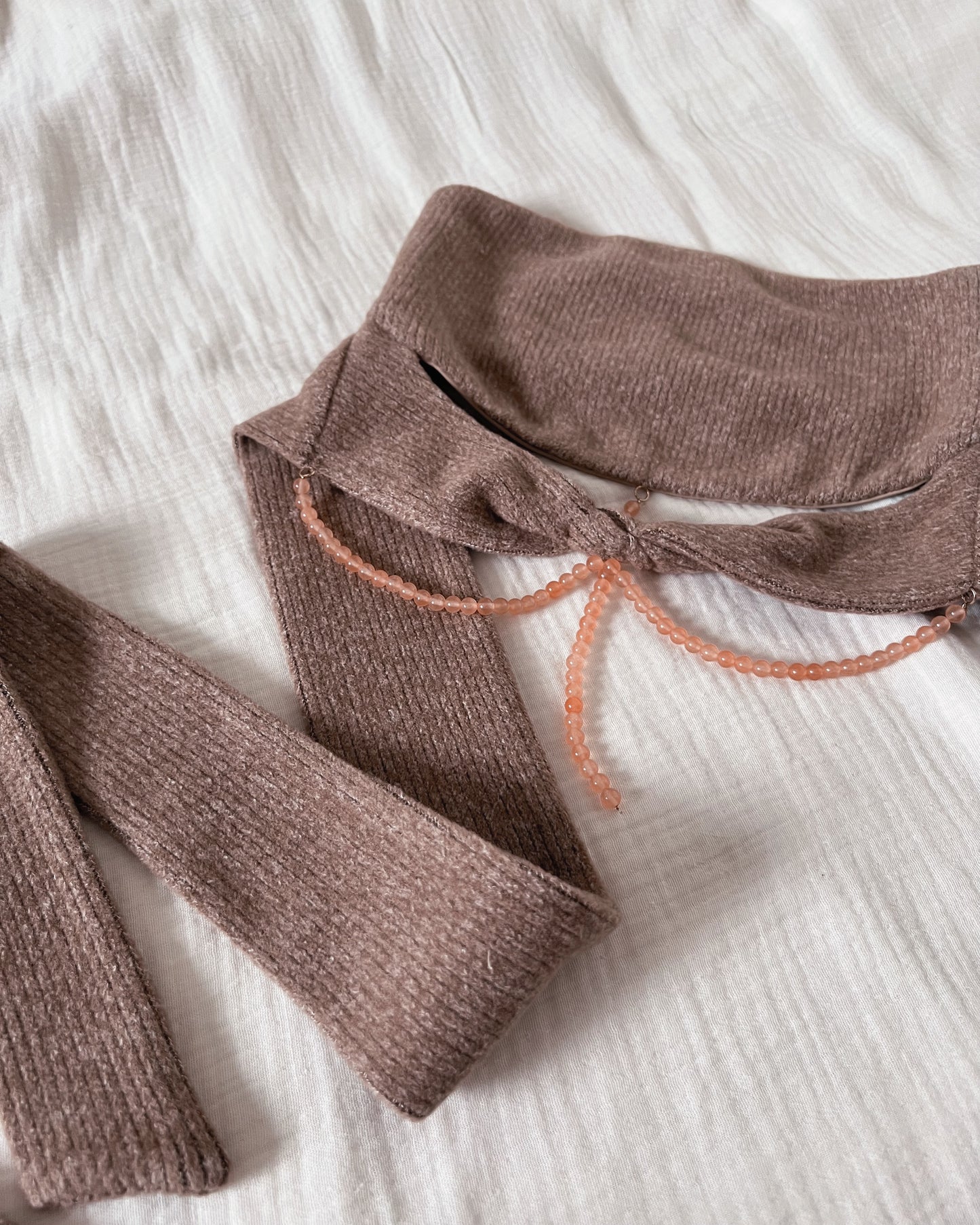 Strapless brown knit top with front twisted knot, long back straps and semi-iridescent beads around waist.